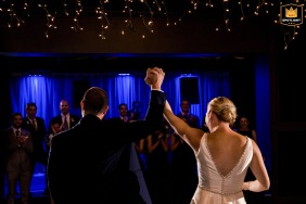 At the River Club in Scituate, Massachusetts, a bride and groom raise joined hands after their first dance. The Wedding photo shows the couple in a moment of celebration.